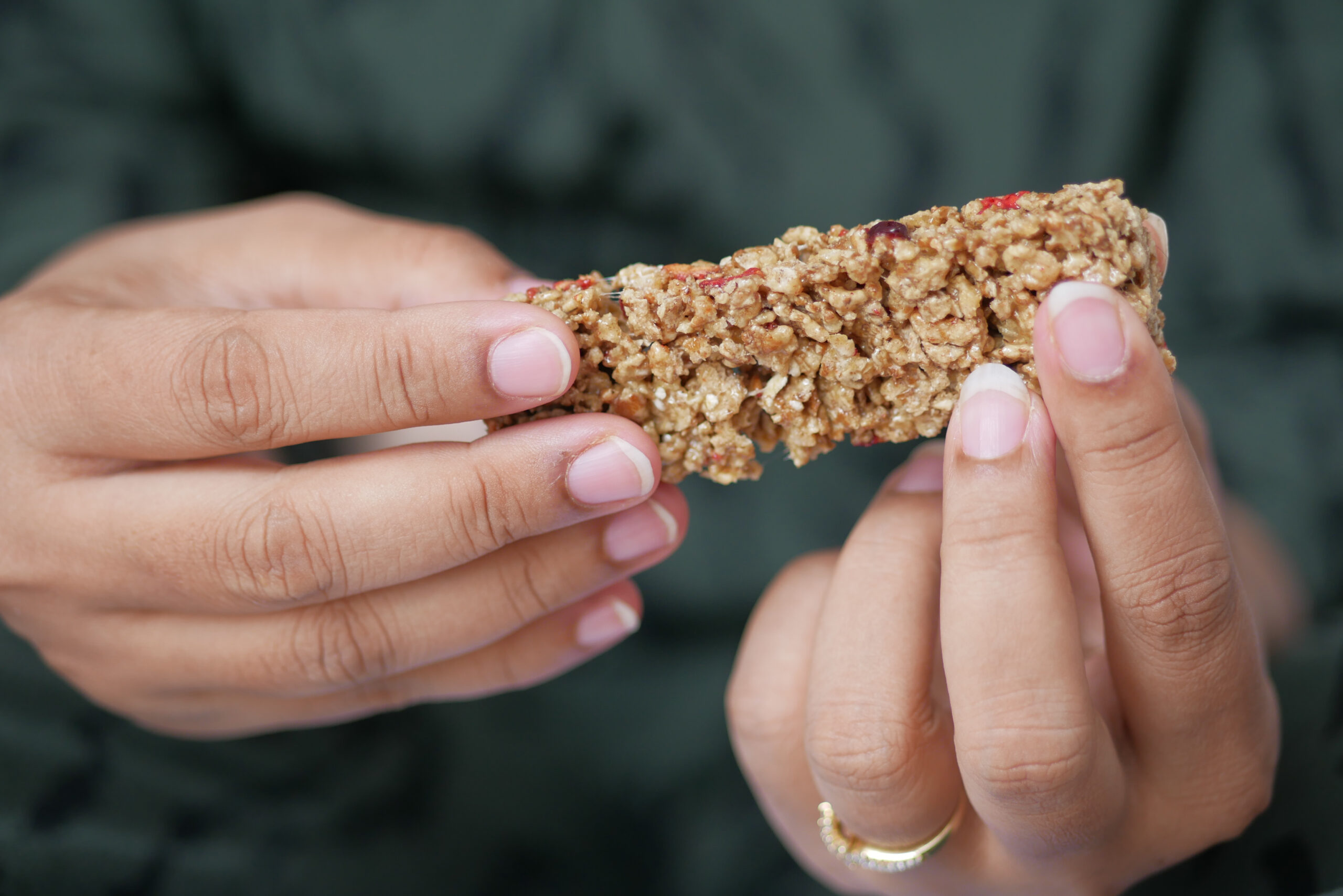 women hand holding a chocolate and oats protein bar