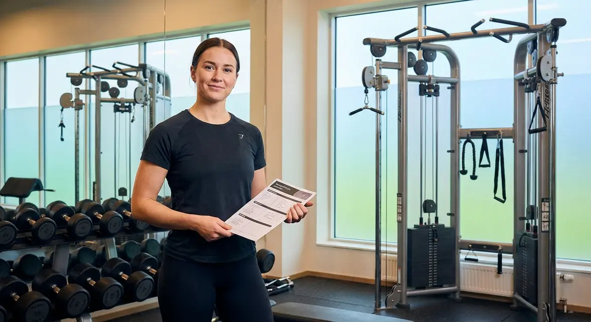 Beginner gym workout routine — confident new gym-goer holding a structured 3-day workout plan